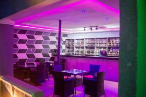 a restaurant with purple lighting and tables and chairs at Jimaco Hotels and Suites in Uyo