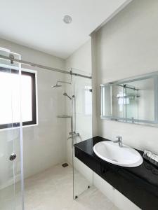 La salle de bains est pourvue d'un lavabo et d'une douche en verre. dans l'établissement SAFFRON Dalat, à Đà Lạt