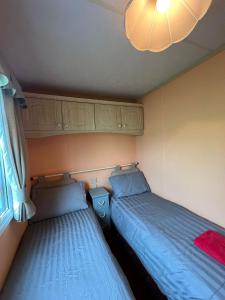 two twin beds in a small room with a window at Beautiful 2 bedroomed mobile home in Aberystwyth