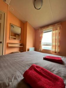 sypialnia z łóżkiem z dwoma czerwonymi ręcznikami w obiekcie Beautiful 2 bedroomed mobile home w Aberystwyth