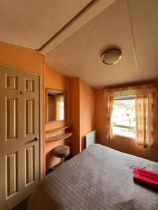 a bedroom with a bed and a window at Beautiful 2 bedroomed mobile home in Aberystwyth