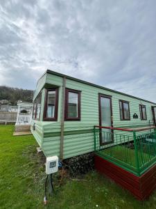 a green house sitting on top of a grass field at Beautiful 2 bedroomed mobile home in Aberystwyth