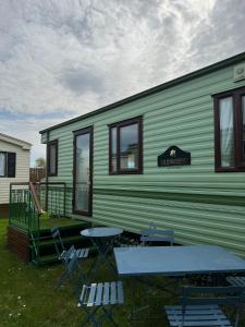 a green house with a picnic table and chairs at Beautiful 2 bedroomed mobile home in Aberystwyth