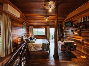 a bedroom with a bed in a room with wooden walls at Cabana Alecrim in Bom Princípio