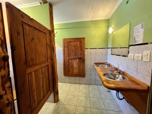 baño con lavabo y puerta de madera en Ankatu Hostel en El Bolsón