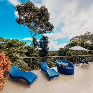 una terraza con 2 sillas azules y una sombrilla en Refúgio em Aldeia dos Camarás, en Camaragibe