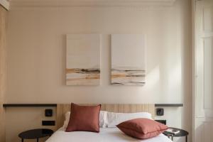 a bedroom with a bed with two paintings on the wall at Líbere Bilbao Ledesma in Bilbao