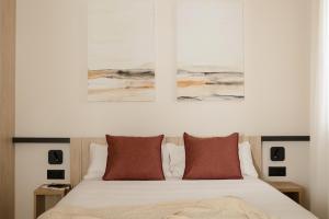 a bedroom with a bed with two paintings on the wall at Líbere Bilbao Ledesma in Bilbao