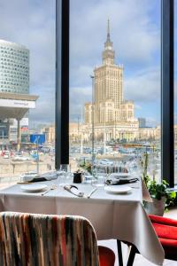 a table in a restaurant with a view of a harbor at Warsaw Marriott Hotel in Warsaw