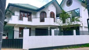 a white house with a fence at Nuwara Eliya Holiday Home in Nuwara Eliya