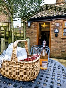 a picnic table with two baskets and a bottle of wine at Strawberry Cottage Close RSPB and Wild Ken Hill - Crabpot Cottages Sheringham in Snettisham