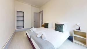 ein Schlafzimmer mit einem großen Bett mit weißer Bettwäsche in der Unterkunft Appartements Rue du Chêne in Mulhouse