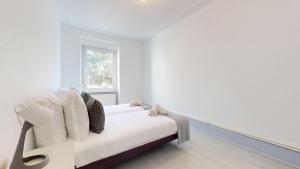 ein weißes Zimmer mit einem Bett und einem Fenster in der Unterkunft Appartements Rue du Chêne in Mulhouse