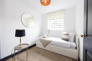 a white bedroom with a bed and a mirror at Luxurious two-bed stay: MCR (with parking) in Manchester