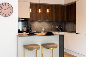 a kitchen with a counter with stools and a clock at Luxurious two-bed stay: MCR (with parking) in Manchester