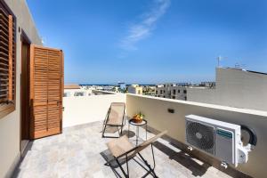 een balkon met 2 stoelen en een televisie op een dak bij I Tre Golfi - Appartamenti a 800 mt dal centro in San Vito lo Capo