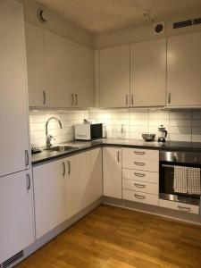 eine Küche mit weißen Schränken, einer Spüle und einer Mikrowelle in der Unterkunft Great 1 bedroom apartment in Lidingö in Kottla