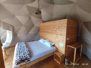 Cama en habitación con pared de madera en Kodai Glamp, en Kodaikanal