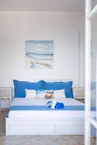białe łóżko z niebieskimi poduszkami i niebieskim pluszowym zwierzakiem w obiekcie Ionian Boutique w mieście Achílleion