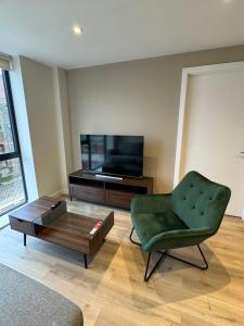 a living room with a green chair and a coffee table at Richmond Row Apartments in Liverpool