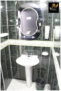 Baño de azulejos negros con lavabo y espejo en Hotel el Duque Internacional, en Bogotá