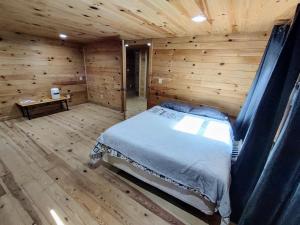 ein Schlafzimmer mit einem Bett in einem Holzzimmer in der Unterkunft Perfectly Imperfect Cabin in Turtletown