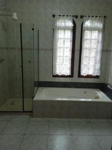 a bathroom with a bath tub and two windows at Hotel Pousada Casa Grande in Joanópolis