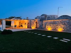 a house with a stone wall and a yard at Trullo Al Guappo d'Oro in Ostuni