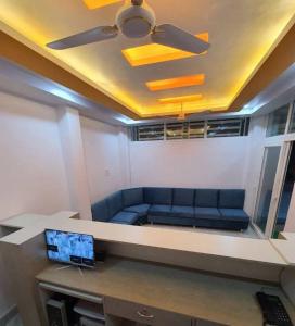 ein Wohnzimmer mit einem blauen Sofa und einem Deckenventilator in der Unterkunft GRG Mahadeva Homes Guest House Prayagraj in Prayagraj