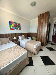 a hotel room with two beds and a painting on the wall at Hotel Atlantico Macaé By Inn House in Macaé