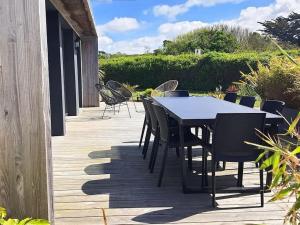 einen Tisch und Stühle auf einer Holzterrasse in der Unterkunft Maison moderne à 2 pas des plus jolies plages ! in Saint-Pabu