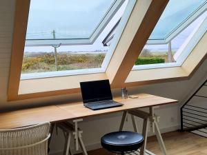 einen Laptop auf einem Schreibtisch mit zwei Fenstern in der Unterkunft Maison moderne à 2 pas des plus jolies plages ! in Saint-Pabu