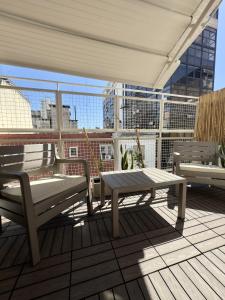 eine Terrasse mit einer Bank und einem Tisch auf dem Balkon in der Unterkunft Hotel Facon Grande in Buenos Aires