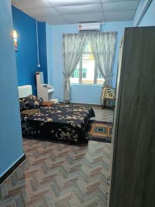 a blue room with two beds and a window at SR KAMPAR HOMESTAY in Kampar