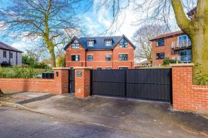 a house with a black gate and a brick fence at Luxury Didsbury 2 Bed Apartment in Manchester