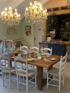 une table en bois avec des chaises blanches et une salle à manger dans l'établissement L'EPICURE- Zimmer Marsanne, à Vacqueyras