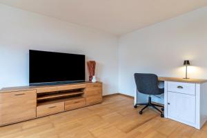 a living room with a tv and a desk and a chair at Fewo Straub in Freudenstadt