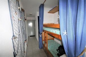 um pequeno quarto com um beliche com cortinas azuis em The sea within sight em Frontignan