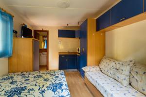 ein kleines Wohnzimmer mit einem Sofa und einem Bett in der Unterkunft Arcobaleno Village H in Marina di Bibbona + 28 Fotos