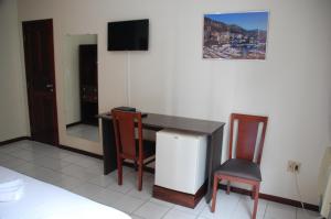 a room with a desk and a tv and a chair at Hotel Netuno Beach in Fortaleza