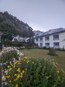 Lukla的住宿－Lukla Himalaya Lodge，一座白色的大建筑,在院子里种着鲜花