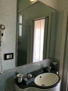 een badkamer met een wastafel en een grote spiegel bij HOTEL AUGUSTUS in Gatteo a Mare
