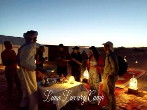 a group of people standing around a table with lights at Luna luxury camp in Merzouga
