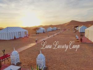 a row of white tents in the desert at Luna luxury camp in Merzouga