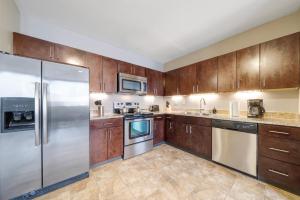 una cocina con armarios de madera y electrodomésticos de acero inoxidable en 1B1B Sky High Luxury Valet Gym Lounge Roku, en Pittsburgh