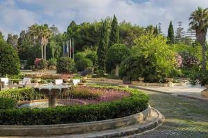 een tuin met een fontein en bloemen in een park bij Stylish Retro Suites in Il-Furjana