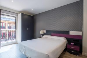Un dormitorio con una cama grande y una ventana en Apartamentos La Albarca, en Hoznayo