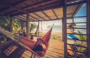een vrouw in een hangmat op een strand bij CABAÑA TELLO SURF in Nuquí