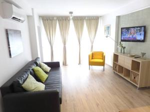 a living room with a black couch and a yellow chair at Room City Estepona Castillo in Estepona