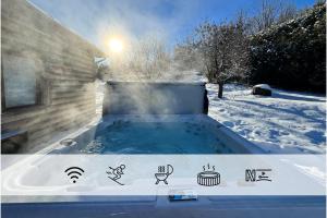 una bañera de hidromasaje en un patio cubierto de nieve en Chalet du Lac - Spa et Vue sur le Lac, en Saint Adolphe D'Howard